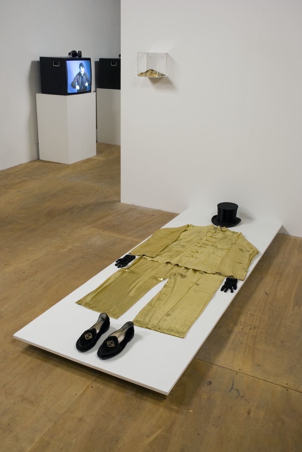 Stuart Sherman, *Nothing Up My Sleeve*. Installation view   
James Lee Byars (platform on floor) The suit of the artist. Gold lame pants and jacket, black silk top hat, black suede monogrammed slippers. Courtesy the Estate of James Lee Byars and Michael Werner Gallery, NY